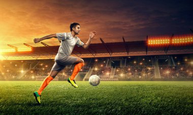 Bir oyun sırasında bir stadyumda bir top ile eylem futbolcu. Dramatik gece gökyüzü ile ışıklandırılmış gece futbol stadyumu