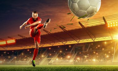 Futbolcu bir oyun sırasında bir stadyumda bir top tekme. Dramatik gece gökyüzü ile ışıklandırılmış gece futbol stadyumu