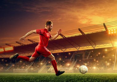 Bir oyun sırasında bir stadyumda bir top ile eylem futbolcu. Dramatik gece gökyüzü ile ışıklandırılmış gece futbol stadyumu