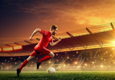 Futbolcu bir topla koşar. Dramatik gece gökyüzü ile ışıklandırılmış gece futbol sahası