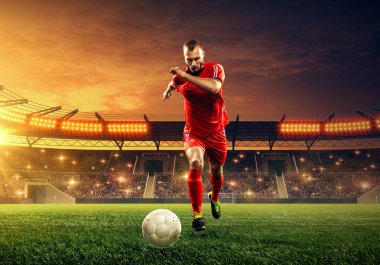 Futbol stadyumunda iş başında olan futbolcu. Aydınlatma ve tribünler ile ışıklandırılmış gece alanı. Gece dramatik gökyüzü