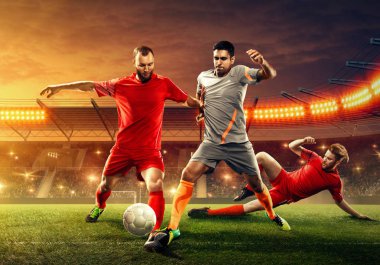 Üç futbolcu taraftarlar cheeering ile profesyonel stadyumda oyun sırasında bir top için mücadele