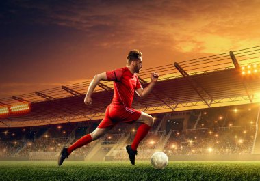 Profesyonel futbolcu hayranları ile ışıklandırılmış bir futbol stadyumunda topla çalışır 
