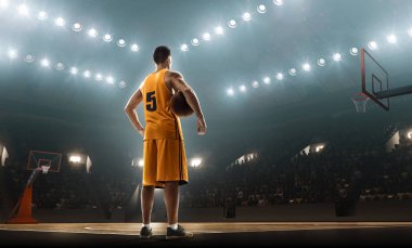 Bir top tutan ışıklandırılmış basketbol sahasında spor üniformalı profesyonel basketbol oyuncusu