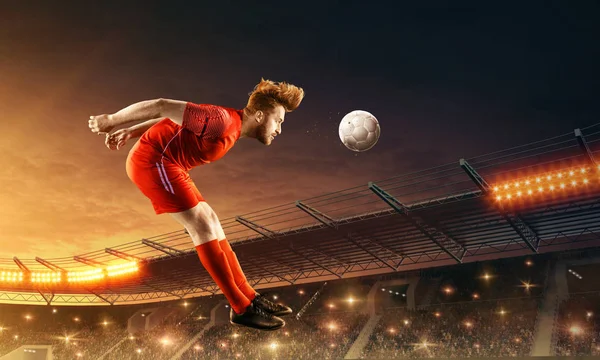 足球运动员用头踢球 带观众和夜空的足球场 — 图库照片