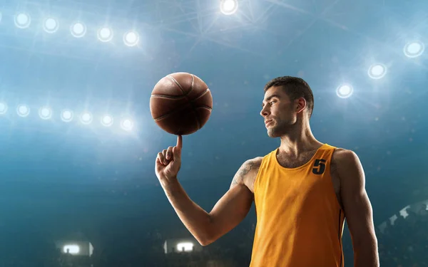 Professional basketball player on a floodlit sports arena turns a ball on his finger