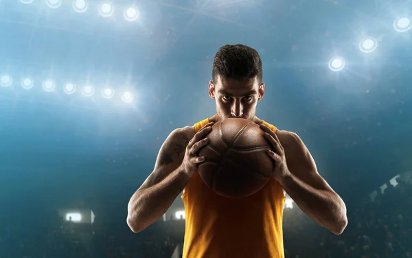 Professional basketball player on a floodlit sports arena with the ball