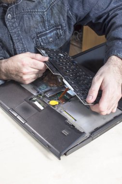 The service technician's hands exchange a broken keyboard in a laptop. clipart