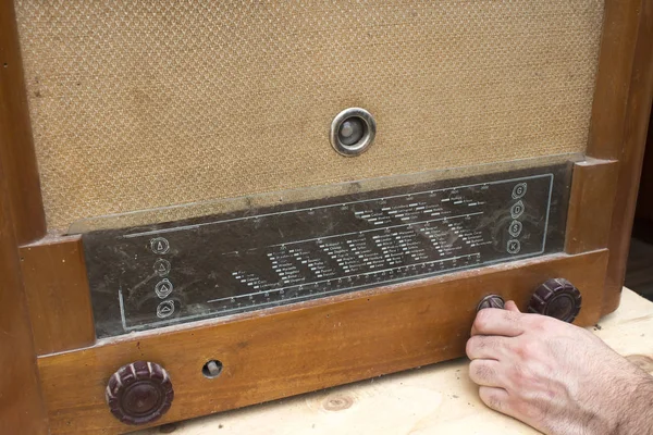 The man\'s hand turns on an old vintage radio lamp.