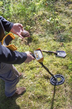 Askeri Arayıcı onun koleksiyonları sunar. Dünya Savaşı'ndan gelen memorabilia için arama. Bir adam bir bomba üzerinden sigorta gösterir. Dedektör bobin ve arka planda kazmacı.