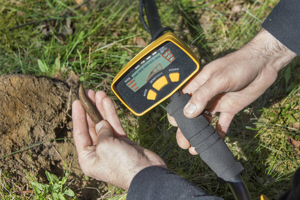 Рука мужчины показывает пулю из винтовки времен Второй мировой войны. Металлоискатель держится в другой руке.
.