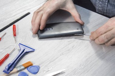 Cep telefonu Servisi. Telefon kapağını çıkarma. Elini aracını kullanarak cep telefonun kapağını kaldırır.