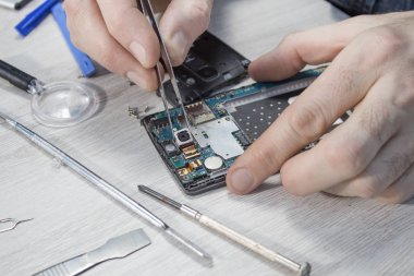 Cep telefonu Servisi. Çalışanın elinde Cımbız kullanarak kamera objektifi kaldırmak.