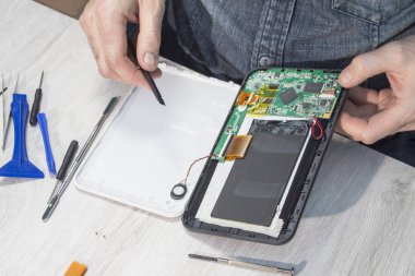 Sitede bir çalışan tarafından vida açılmış tablet. Bir elektronik hizmet çalışan eller hasarlı tablet sökün.