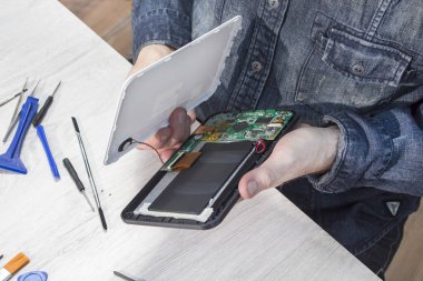 Elektronik hizmet çalışan tablet'ın tümleşik devre elinde tutar. Elektronik hizmet istasyonunda çalışıyorum. Tablet onarım.
