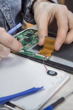 Elektronik hizmet istasyonunda çalışıyorum. Tablet onarım. Elinde bir elektronik hizmet çalışan hasarlı tablet sökün.