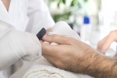 Onun tırnak içinde belgili tanımlık palmiye bir adamın bir tırnak törpüsü ile Şevval özçelik güzellik güzellik salonu manikür tedavisi sırasında beyaz tek kullanımlık eldiven manicures