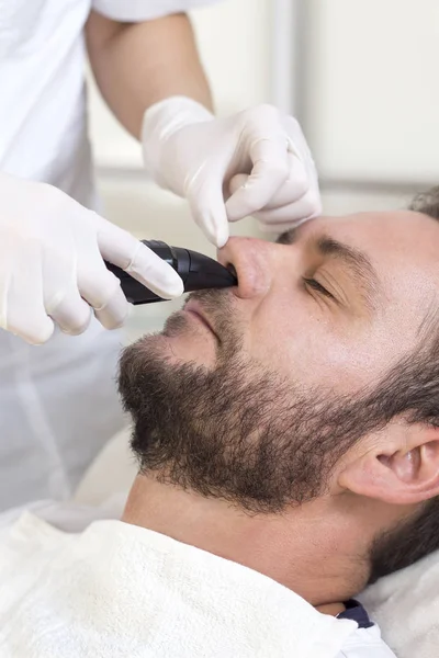 Man in a beauty salon during a nose hair removal surgery