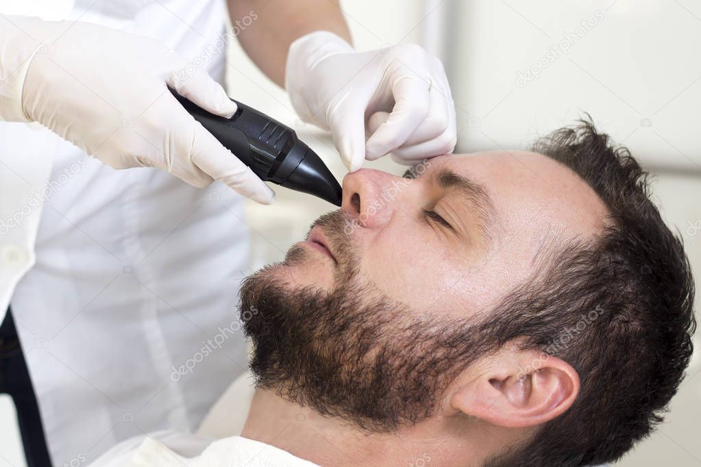 A man in a beauty salon during a nose hair removal surgery