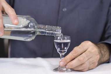 adam bir bardak koruyor ve votka şişe içine dökülen.