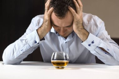 Alkol bela. Depresif adam elinde kafasıyla masada oturur. Bir bardak viski onun önünde duruyor.
