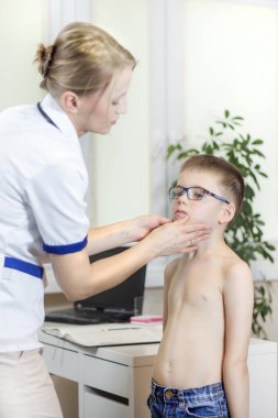 Doktor bir doktor ofisinde bir çocuk gözlüklü bademcikler inceleyerek tıp sırasında.