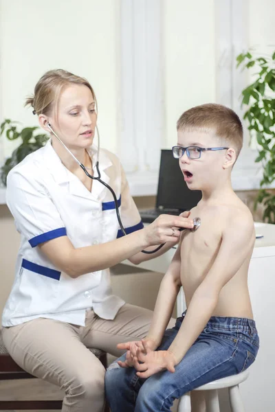 在儿科医生用听诊器进行体检时 男孩通过张开的嘴深深呼吸 — 图库照片