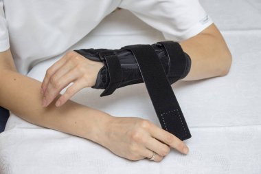 Kadın bilek sabitleyici onun koluna koyar..