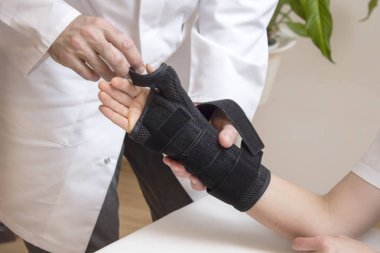 Ortopedik uygulayıcı bir kara el sabitleyici bir kadın hastanın yandan varsayar.