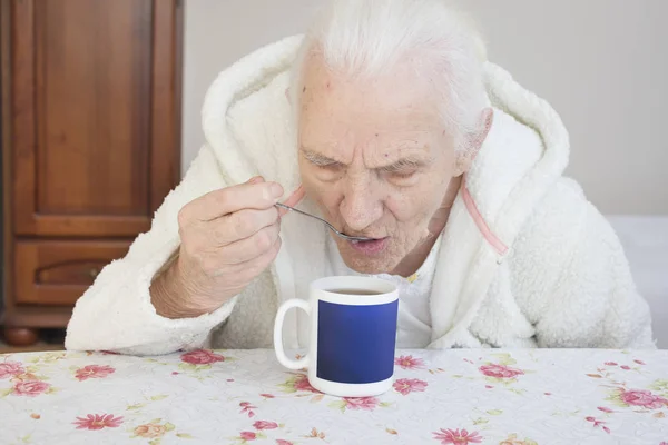 Una Anciana Pelo Gris Sienta Una Mesa Bebe Una Cucharadita — Foto de Stock