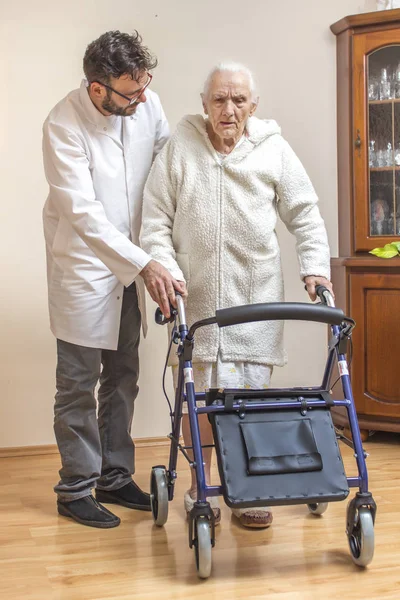 男性看護師は 歩行者 バルコニーの助けを借りて歩くために老婦人を助けます — ストック写真