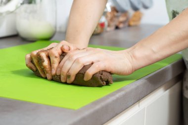 Eller üzerinde yeşil bir masa mutfak tezgahına Noel kurabiyeleri için bir pasta yapmak.