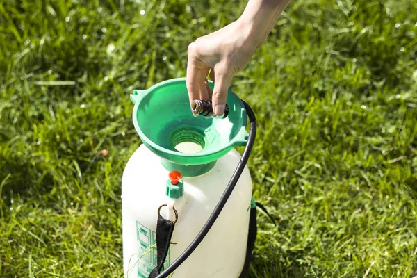 woman\'s hand doses the amount of the agent by pouring into the sprayer.