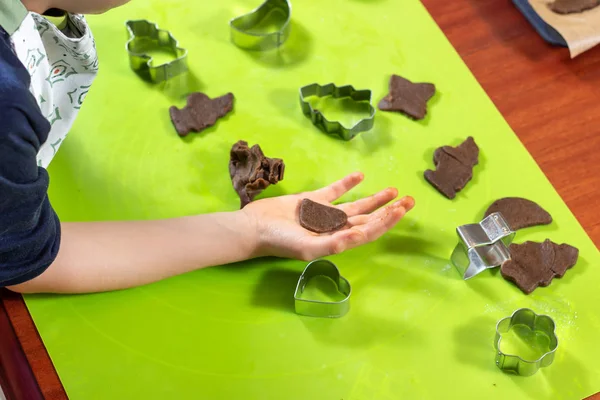 蛋糕的心脏躺在孩子的手上 金属模具位于绿色硅胶咖啡桌上被挤出的棕色面团形状中 — 图库照片