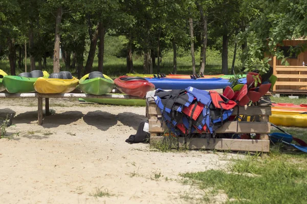 Kayak rental. Colored kayaks placed on racks are on the beach. Kapok and paddles arranged in a wooden container.
