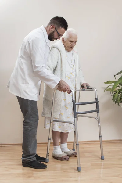 医療リハビリテーションバルコニー おばあちゃんは 歩行者の助けを借りて歩くことを学び 看護師の助けを借りて — ストック写真