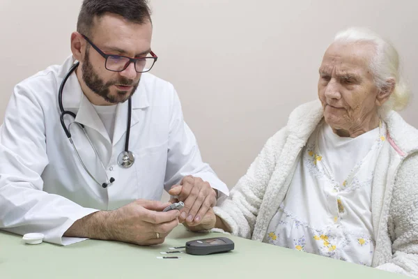 외투와 안경을 당뇨학자가 오래된 여성의 수준을 검사합니다 — 스톡 사진