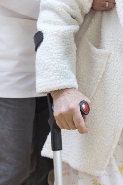 beyaz bir sabahlık ve gecelik çok yaşlı bir kadının el bir sopa sapı tutar. Hemşire, koltuk altı altındaki kadını belay ve destek.