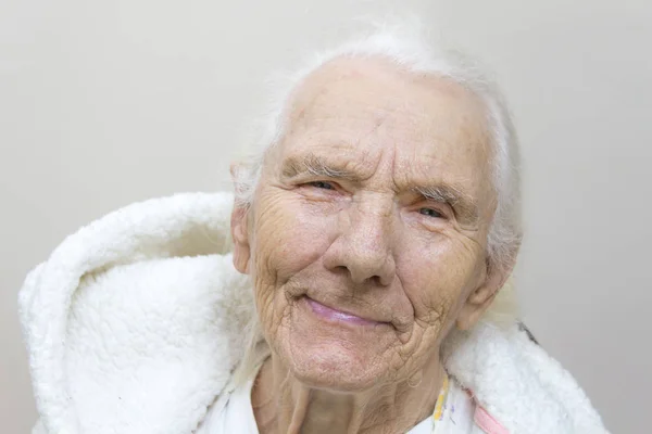 一个很老的灰色女人的脸没有牙齿 一个微笑的白发苍苍的老妇人穿着浴袍 头戴头巾的肖像 — 图库照片