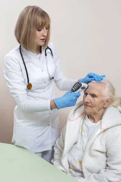 Arzt Einmalhandschuhen Untersucht Eine Alte Frau Messung Der Temperatur Mit — Stockfoto