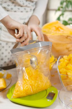 Kadın plastik bir torbaya sarılmış rendelenmiş taze balkabağı kaşık yayıyor..