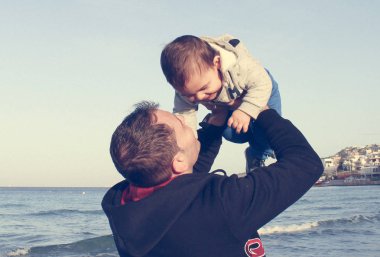 Baba ve bebek çocuk üzerinde kumlu plaj sonbahar, yüz minderlerle mutlu aile