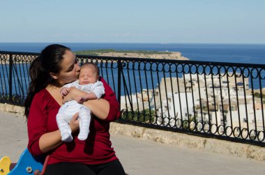 Anne kırmızı t-shirt holding bir ay önce yeni doğan bebek çocuk Park, deniz içinde belgili tanımlık geçmiş