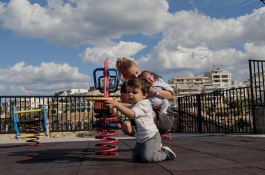 Yeni doğan bir bebek tutan ve yürümeye başlayan çocuk parkı - aile zaman kavramı ile oynayan genç sarışın anne
