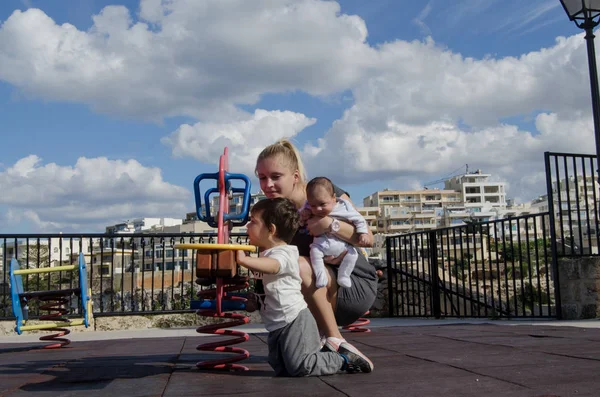 Joven Madre Rubia Sosteniendo Bebé Recién Nacido Jugando Con Niño — Foto de Stock