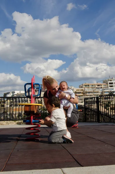 Joven Madre Rubia Sosteniendo Bebé Recién Nacido Jugando Con Niño — Foto de Stock