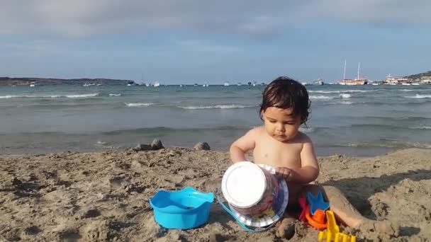 Bambino sulla spiaggia di sabbia che gioca con la sabbia — Video Stock