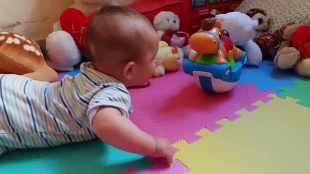 Menino Bonito Sua Barriga Tentando Alcançar Brinquedos Playmat Colorido — Vídeo de Stock
