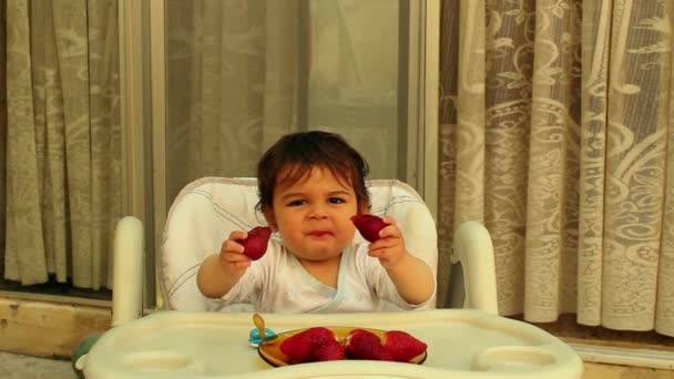 Jongetje in kinderstoel eten aardbeien — Stockvideo