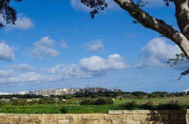 Qawra, Malta manzara binaların mavi gökyüzü ve beyaz bulutlar ve taş ile Kartpostal duvar veya sanat tuval